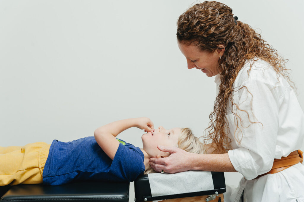 Kalamazoo Michigan chiropractor smiles down at a smile boy during his adjustment